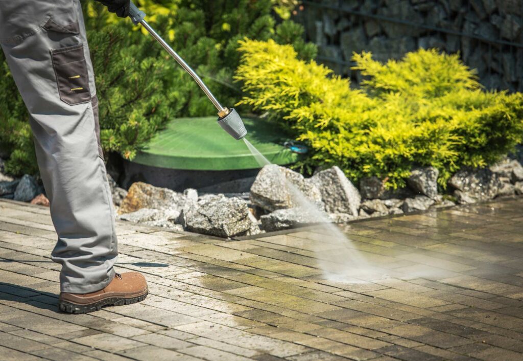 Professional cleaning paver patio with a pressure washer as part of routine hardscape maintenance.